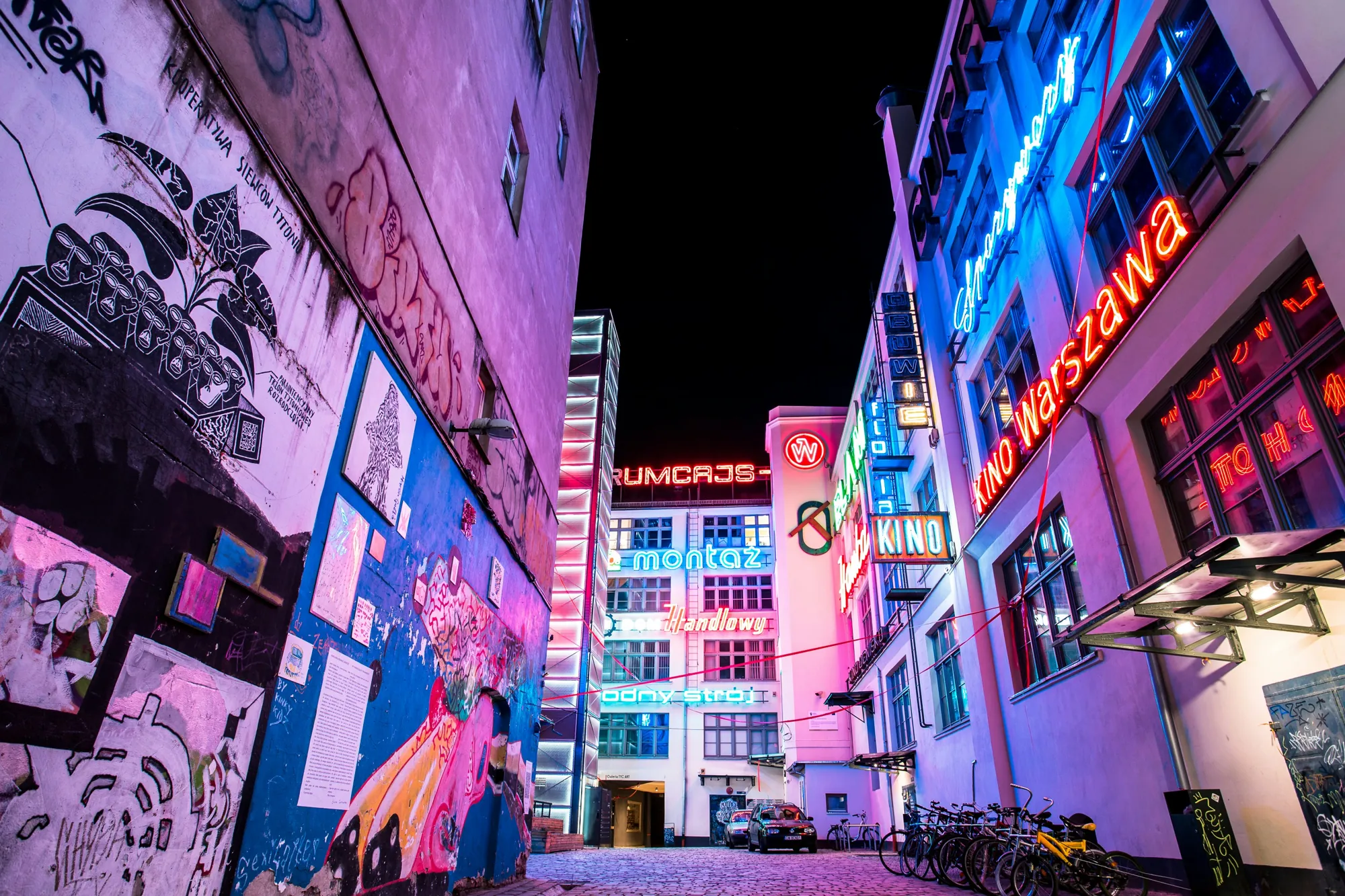Neon signs glowing in a Wrocław courtyard at night