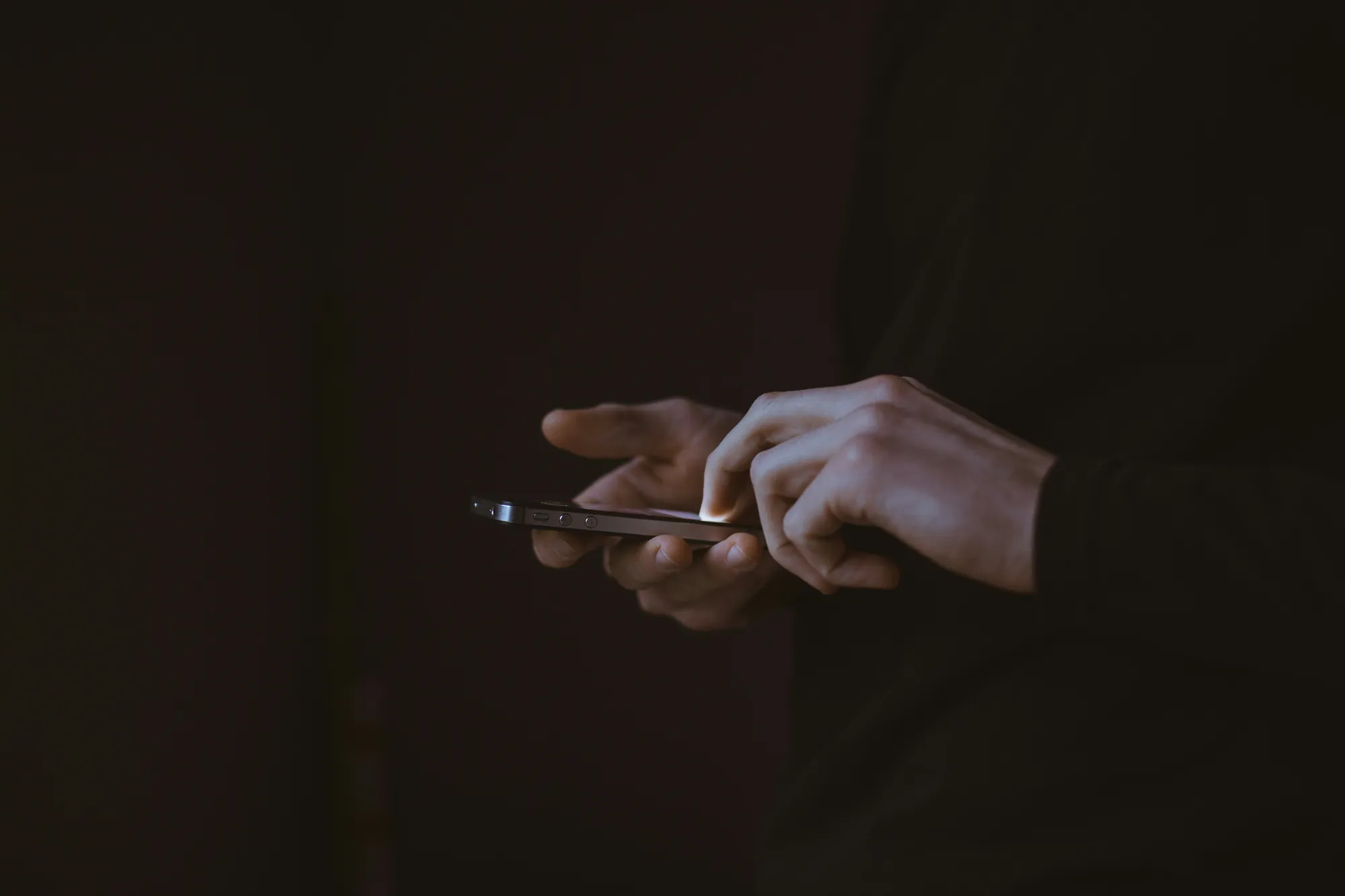 Hands typing on a phone in the dark
